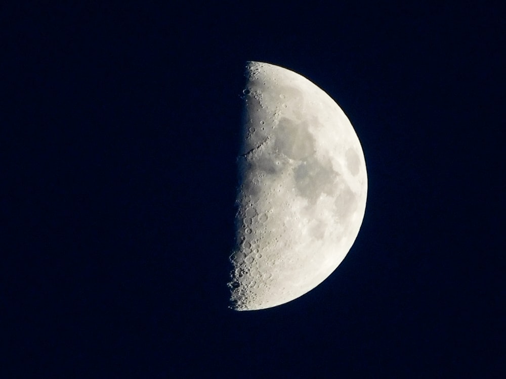 a half moon is seen in the dark sky