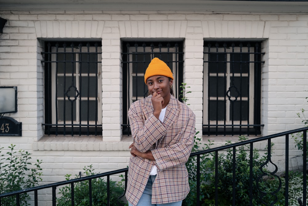 a man wearing a yellow hat standing in front of a building