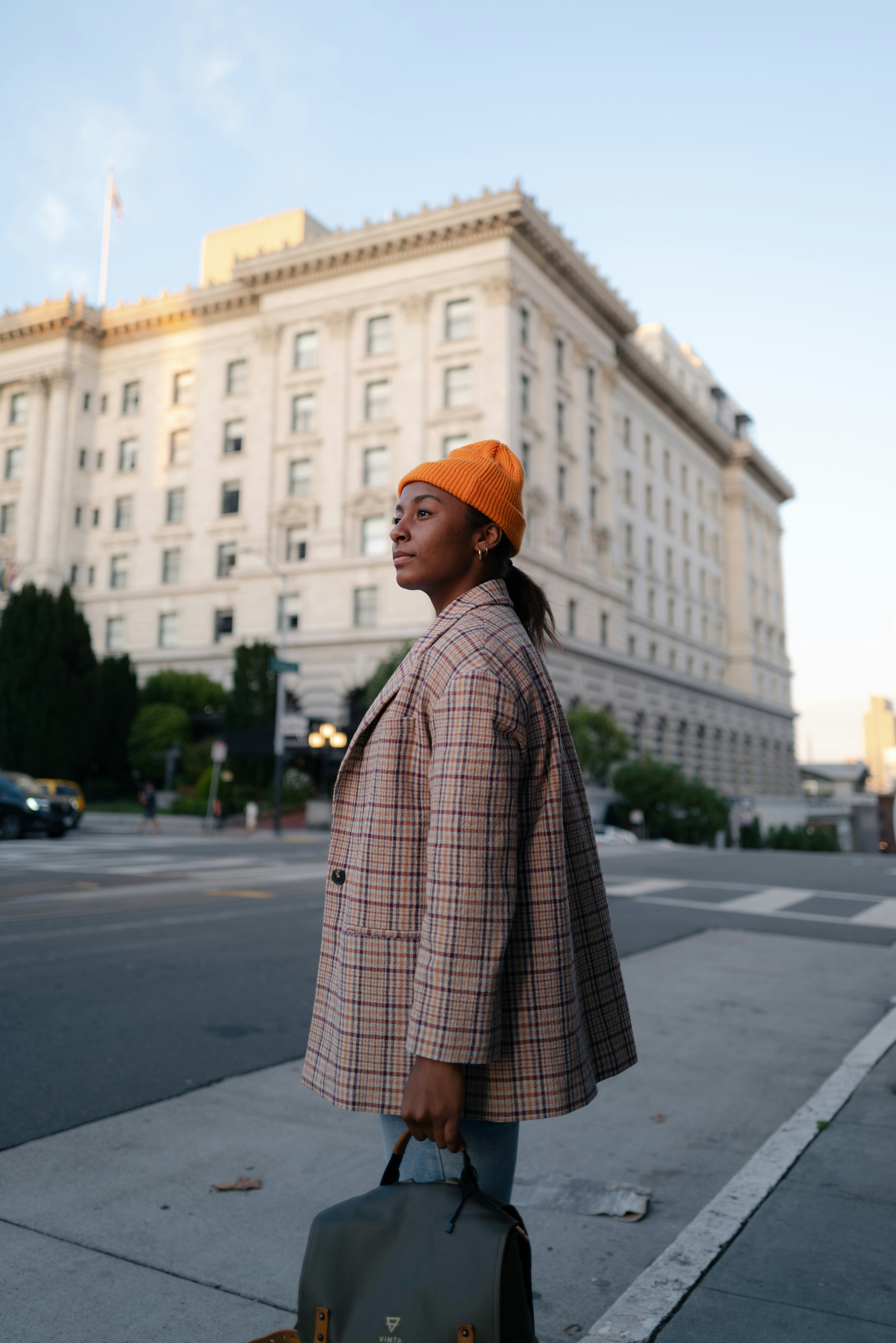 Eine Frau steht mit einem Koffer auf dem Bürgersteig