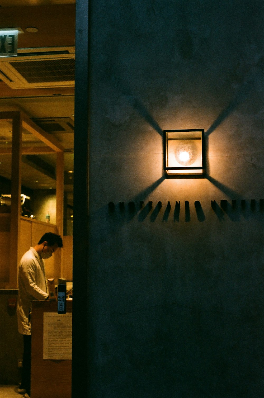 a man standing in front of a wall mounted light