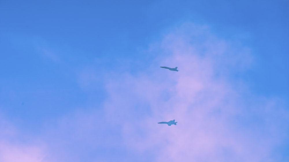a couple of planes flying through a blue sky