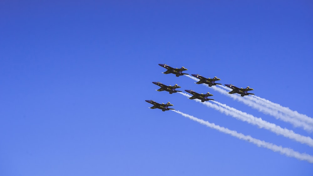 a group of fighter jets flying through a blue sky