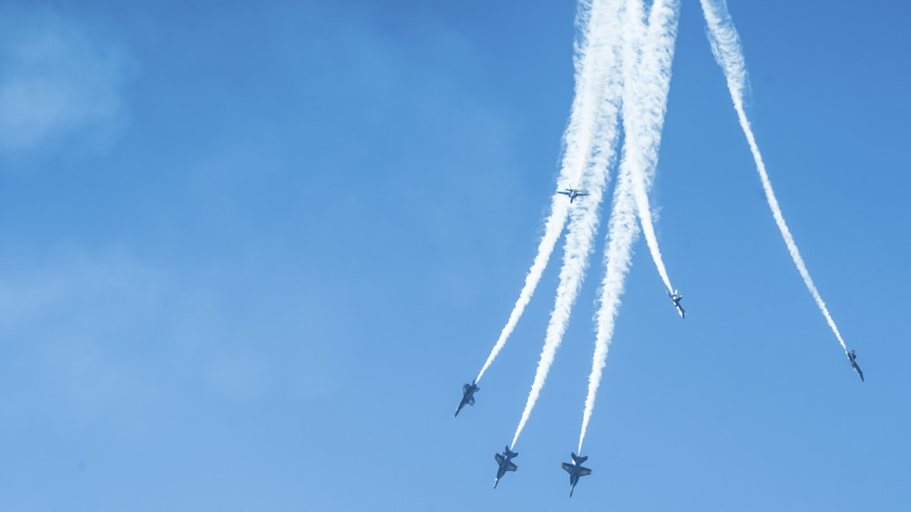 a group of jets flying through a blue sky