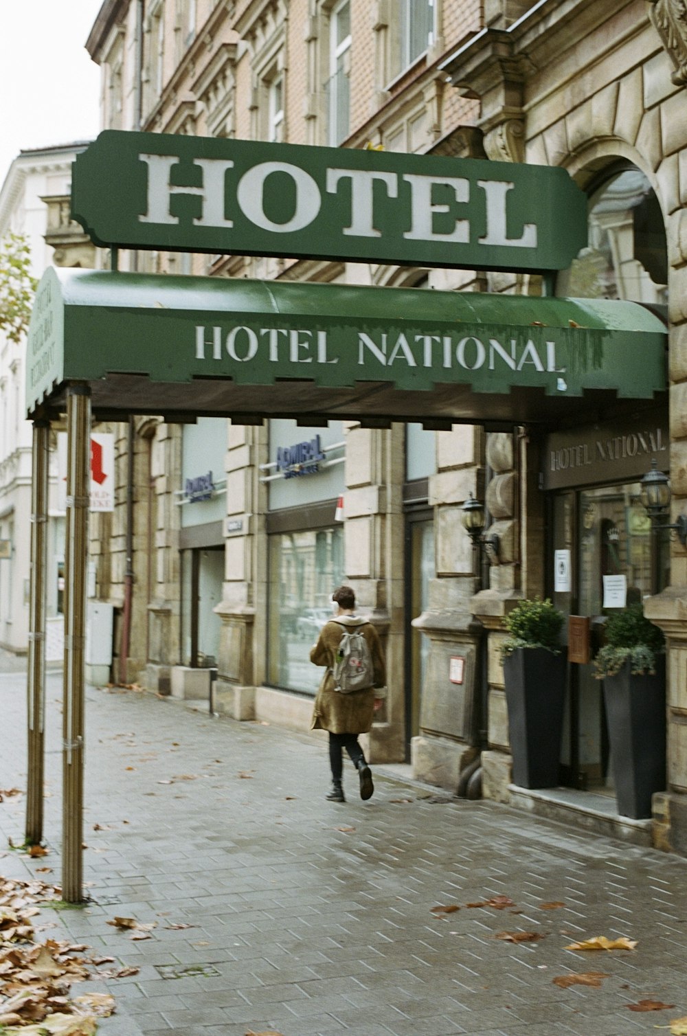 a woman walking down a street under a hotel sign