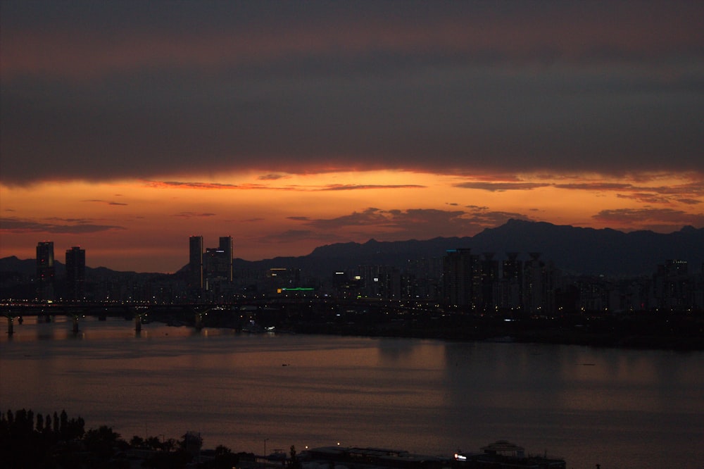 a sunset view of a city with a bridge in the foreground