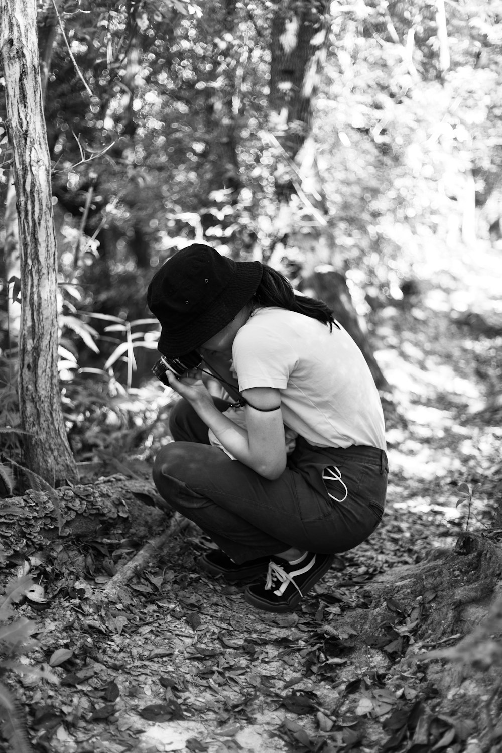 a person kneeling down in the woods with a camera
