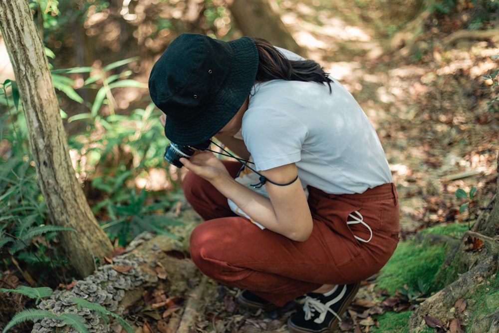 a person kneeling down in the woods with a camera