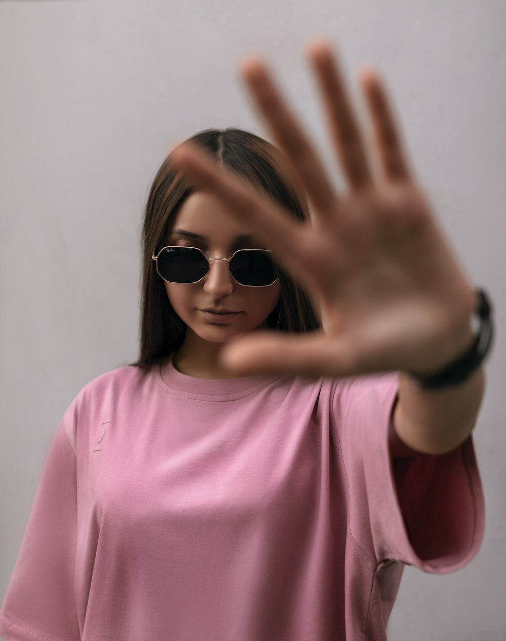 a woman wearing sunglasses making a stop sign