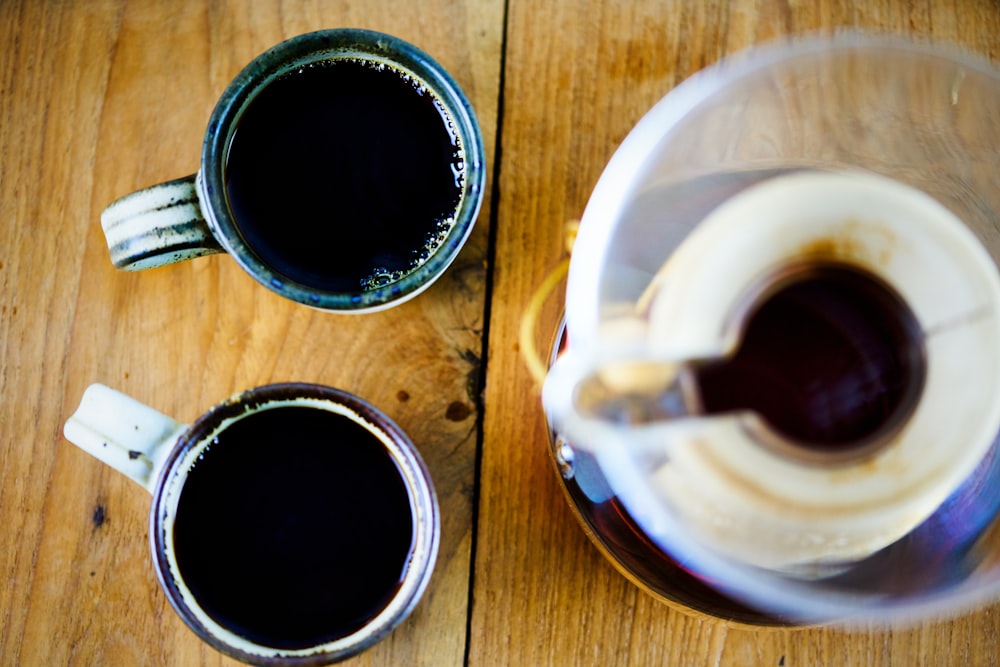 two cups of coffee sit on a wooden table