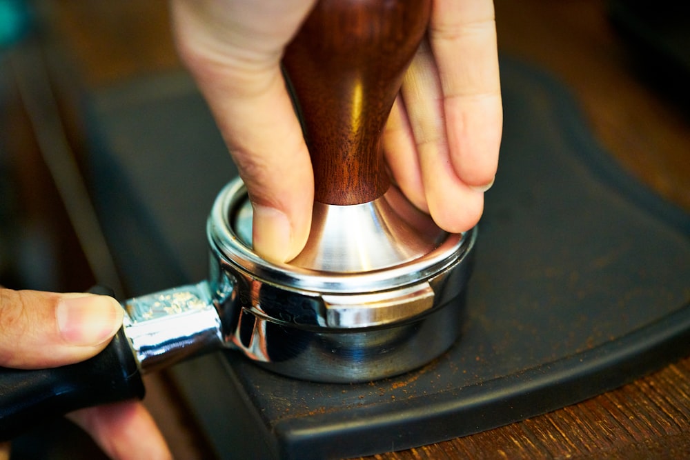 a person holding a metal container with a wooden handle