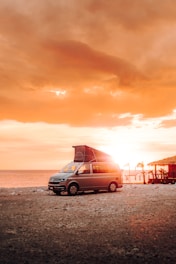 a van parked on the beach at sunset