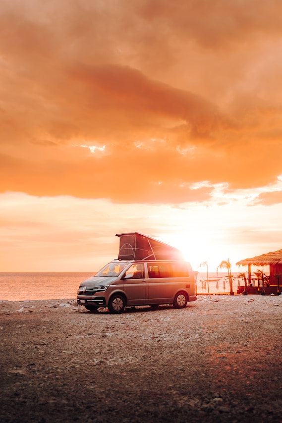 a van parked on the beach at sunset