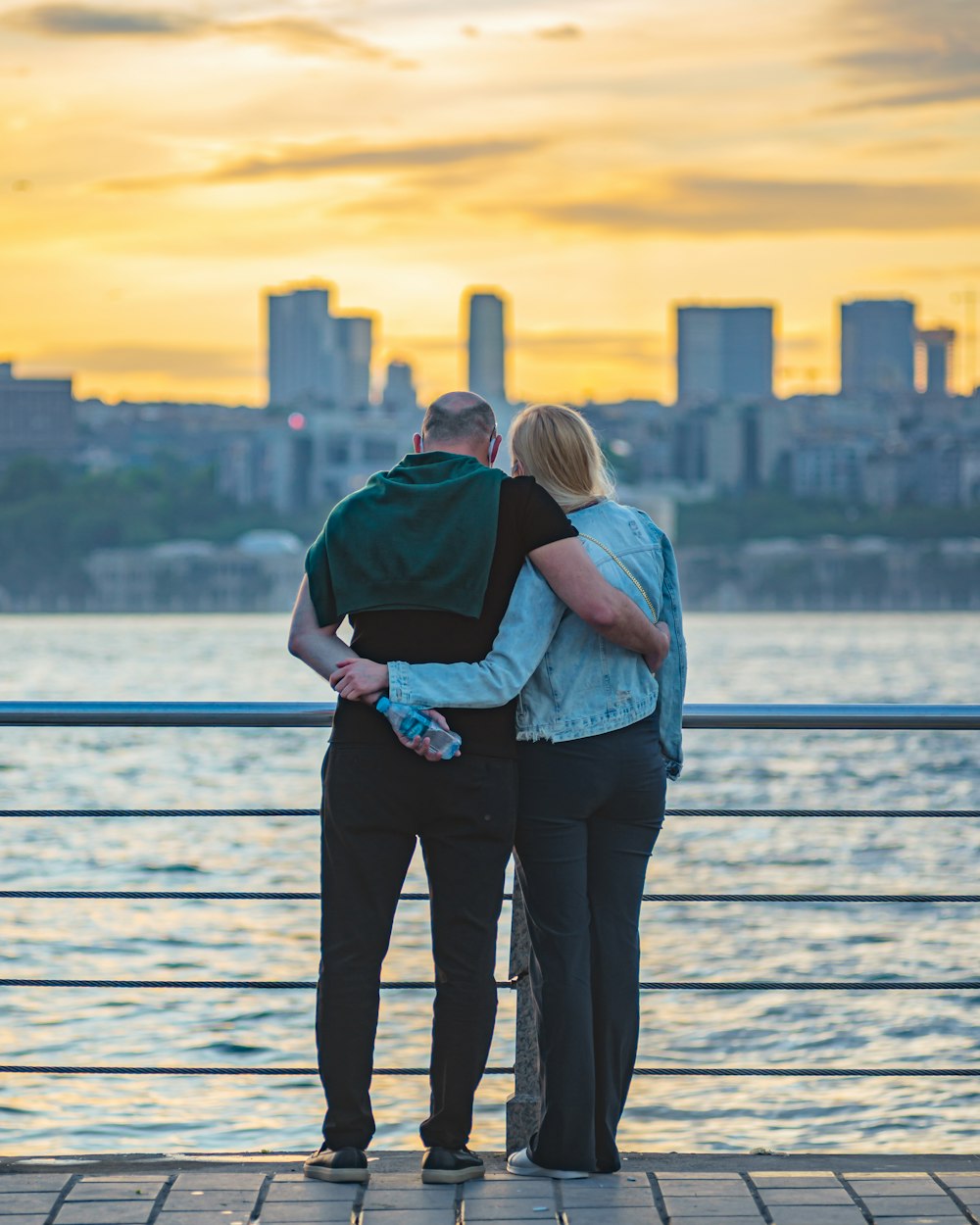 a man and a woman standing on a pier looking at the water