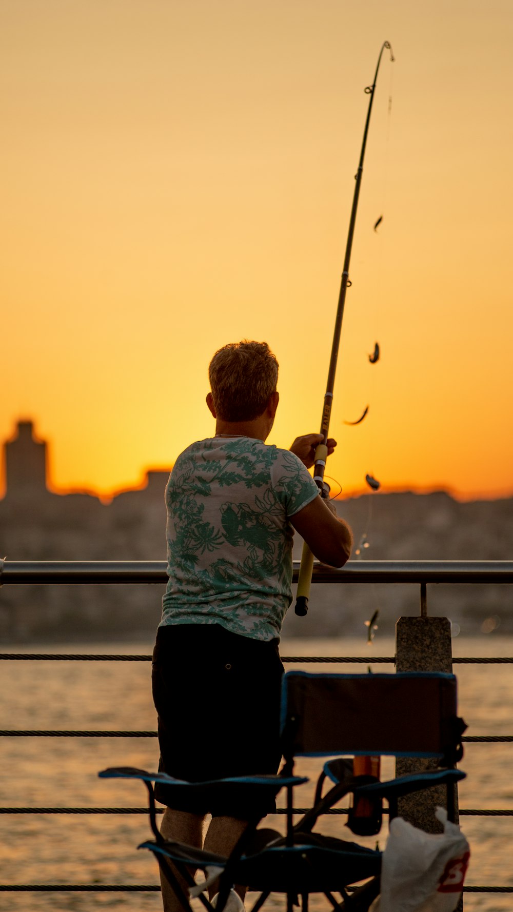a man fishing on a boat at sunset