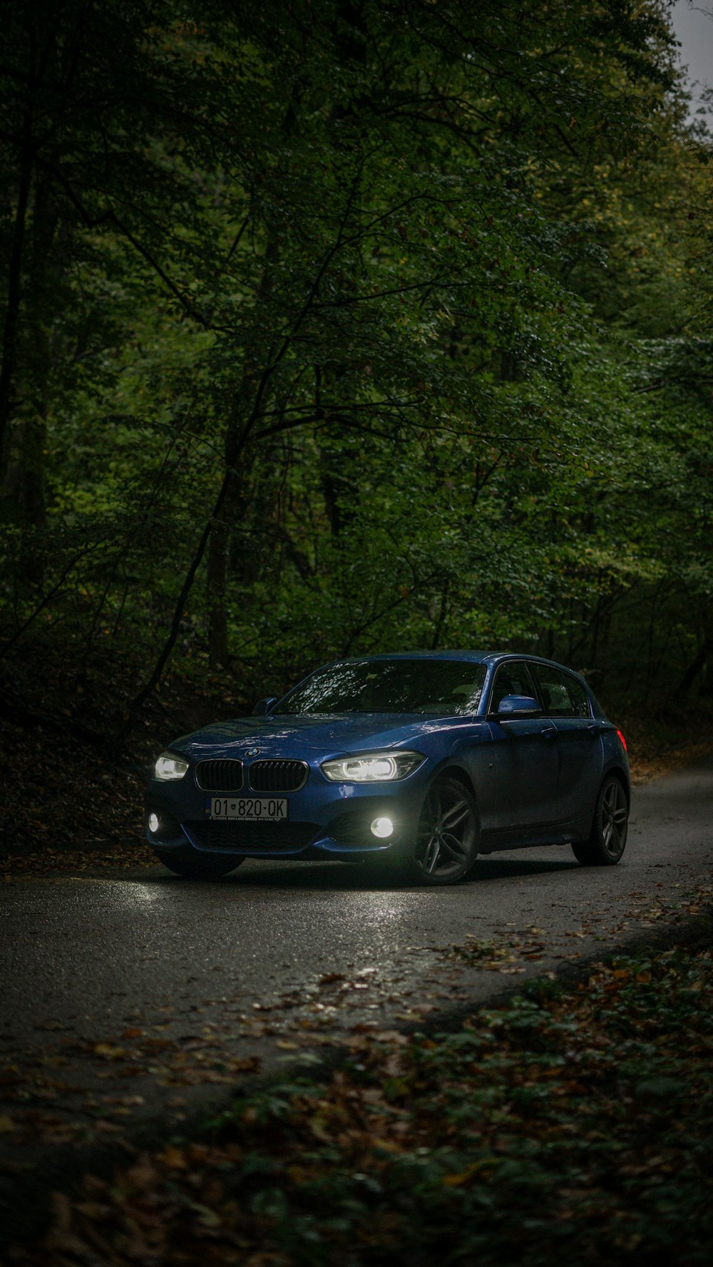 a blue car driving down a forest road