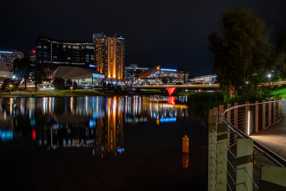 uma cena noturna de uma cidade com um rio e uma ponte