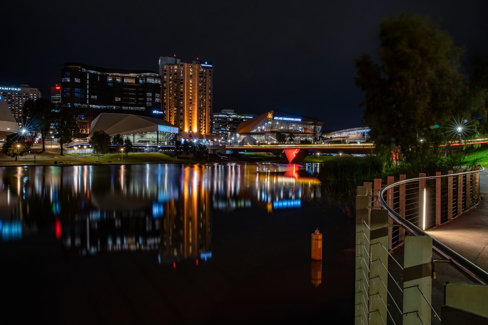 a night scene of a city with a river and a bridge