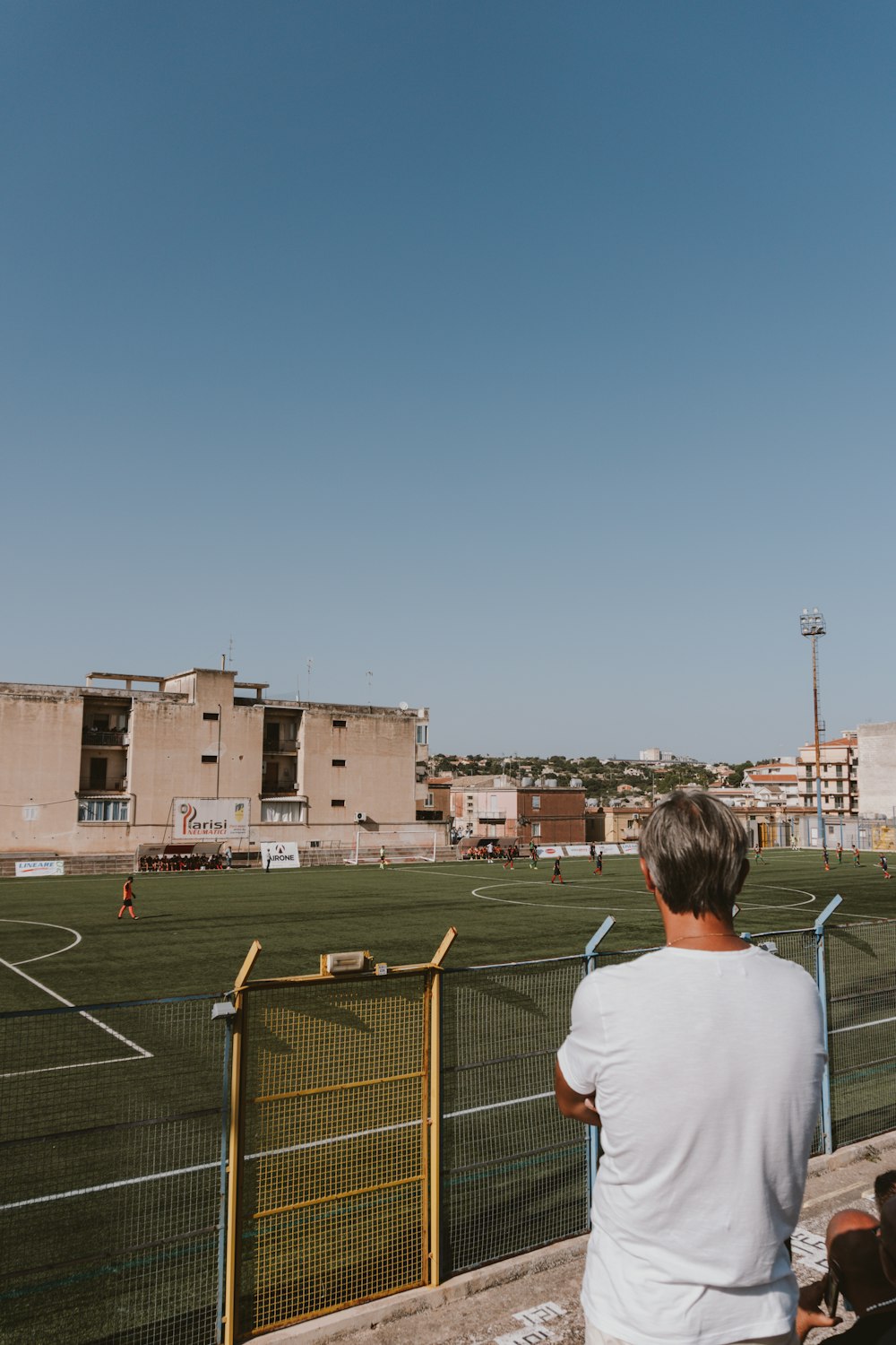 a man sitting on a bench looking at a soccer field