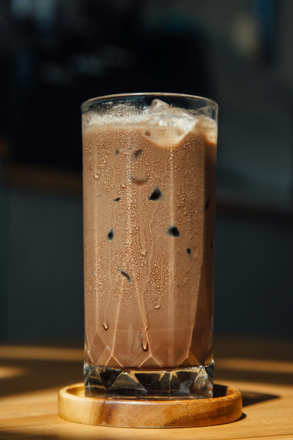 a tall glass filled with liquid sitting on top of a wooden table