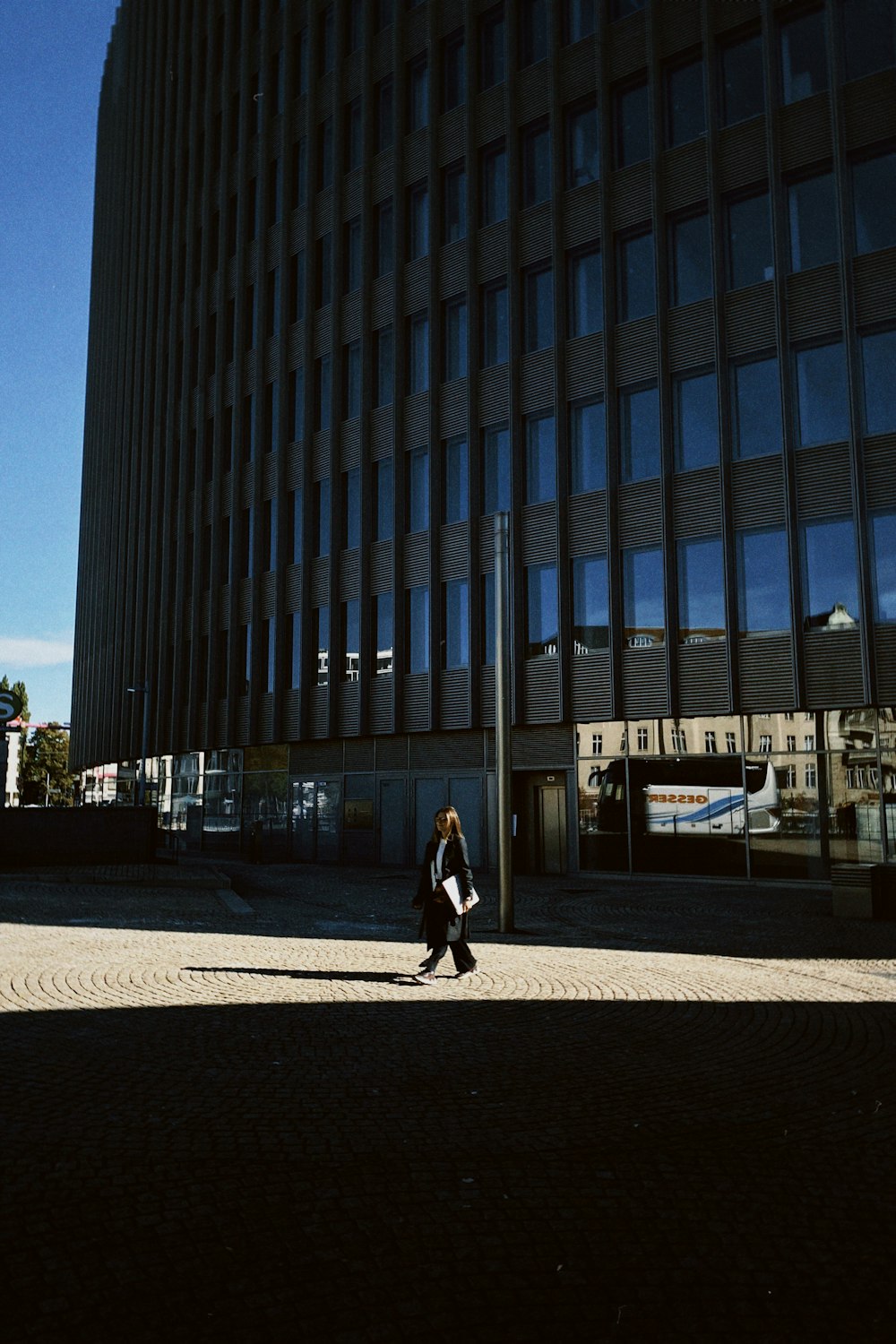 a woman walking down a street past a tall building