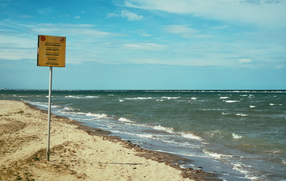 a sign on a beach near the ocean