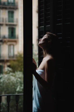 A peaceful moment showing a woman wrapped in a plush towel, her skin glowing softly in natural light.