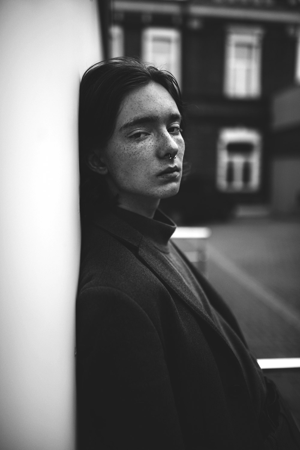 a black and white photo of a man leaning against a wall