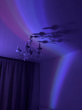 A sparkling chandelier casting colorful reflections against a dark ceiling, reminiscent of early 2000's glitter aesthetics.