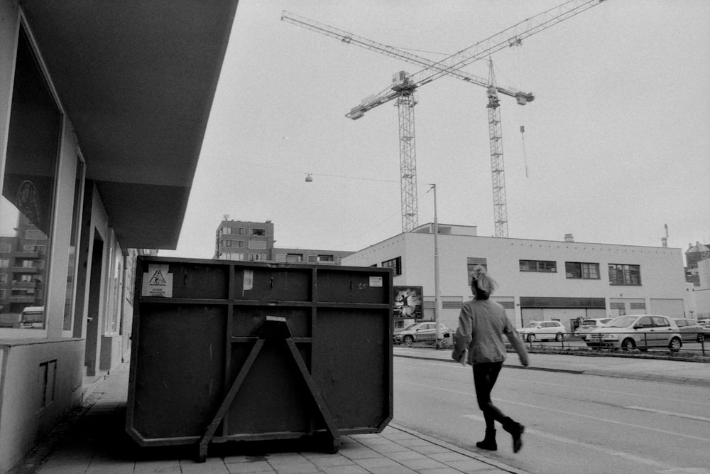 a black and white photo of a man walking down the street