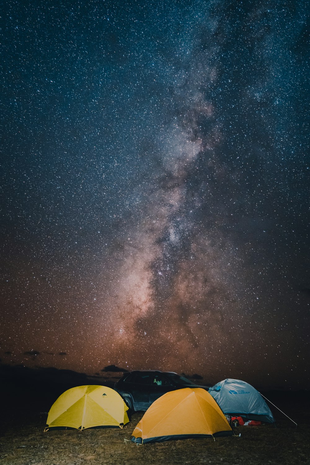 a couple of tents sitting on top of a field under a night sky