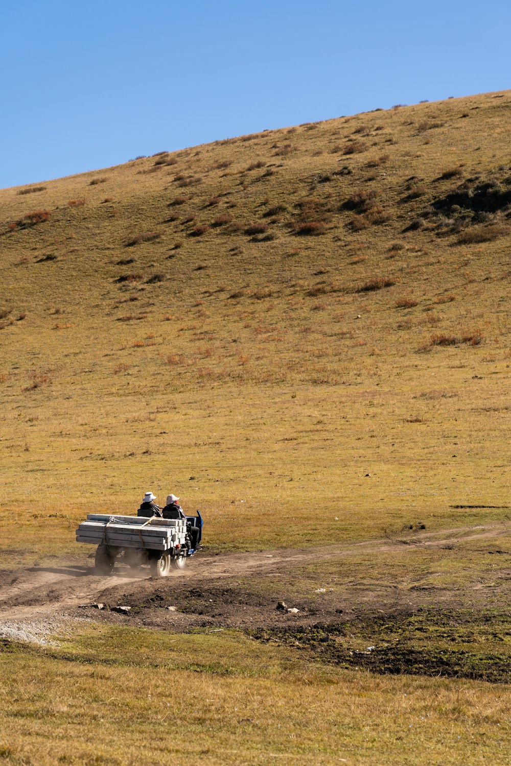 two people sitting on a bench in the middle of a field