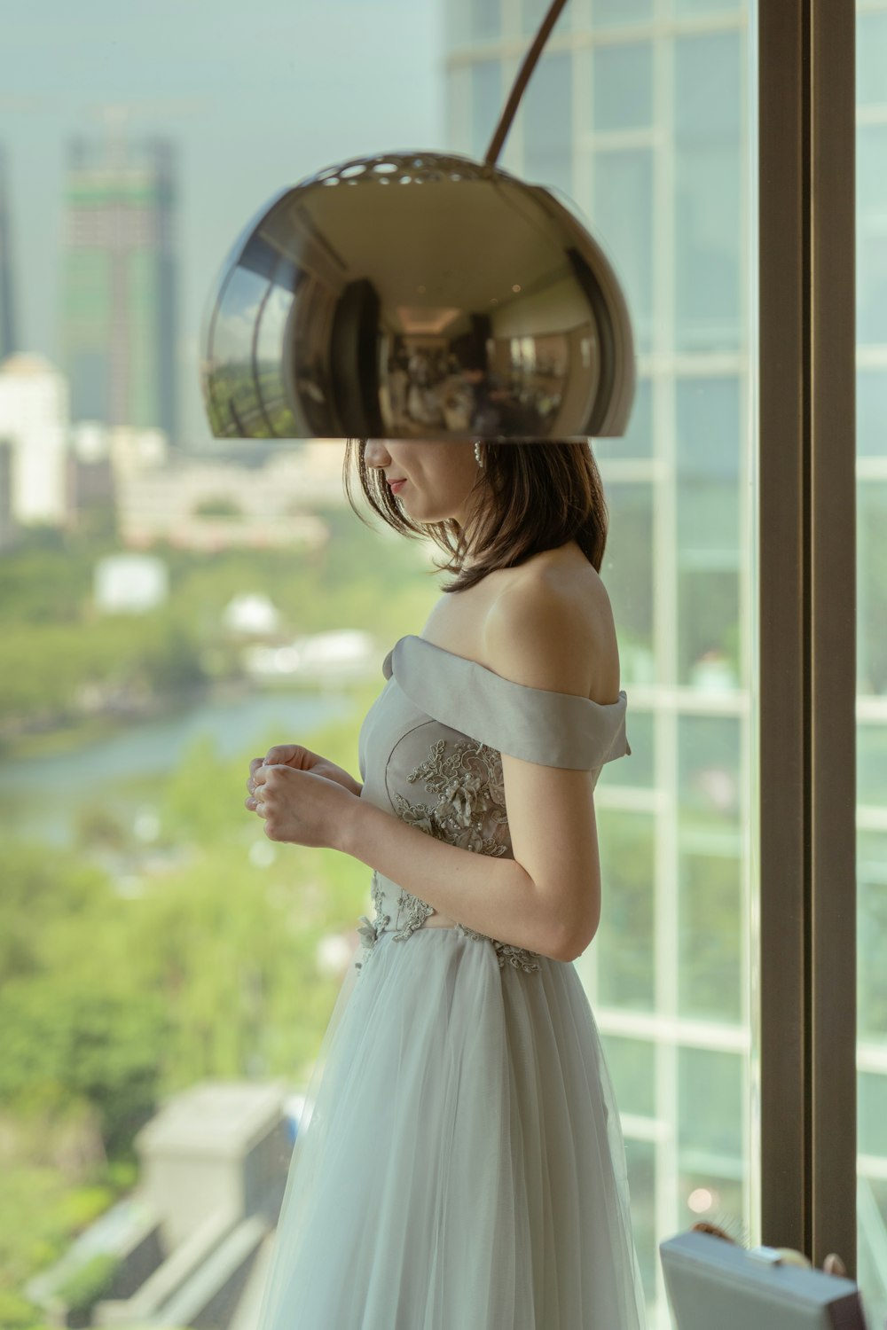 a woman in a white dress looking out a window