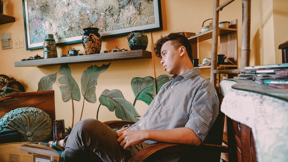 a man sitting in a chair in front of a painting