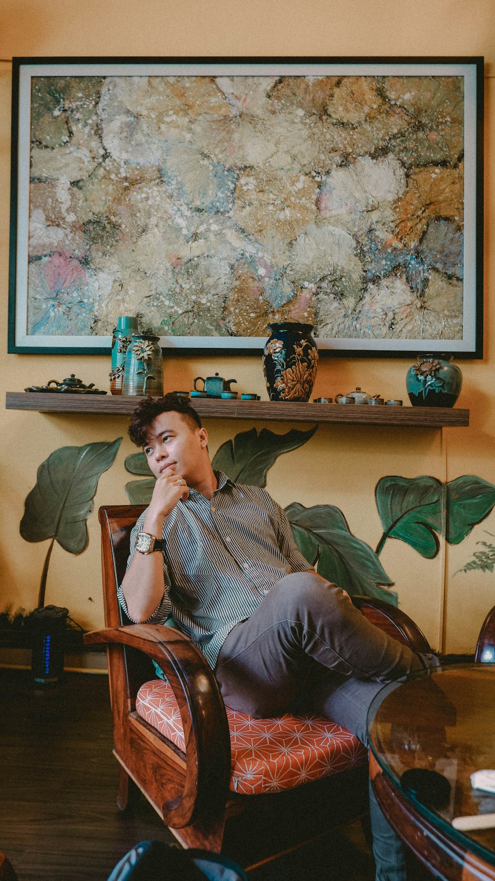 a man sitting in a chair in front of a painting