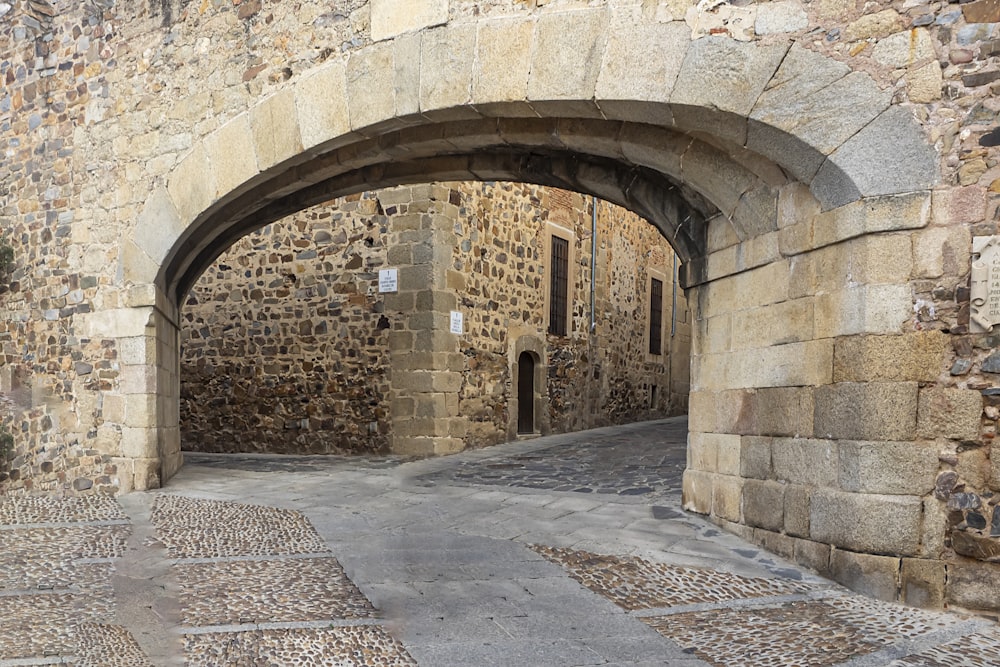 a stone building with an arched doorway and cobblestone walkway