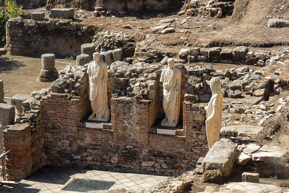 un gruppo di statue sedute sulla cima di un muro di pietra