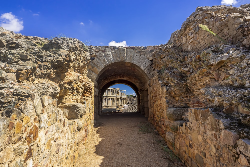 a stone tunnel with a building in the background