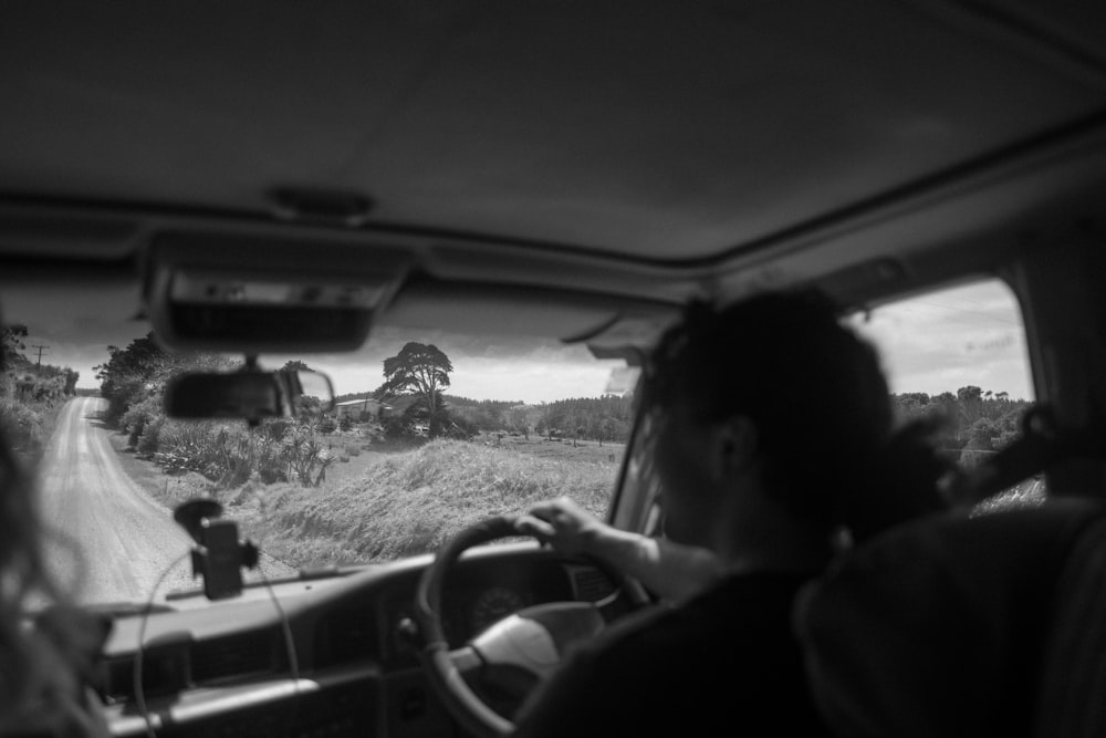 a man driving a car down a rural road