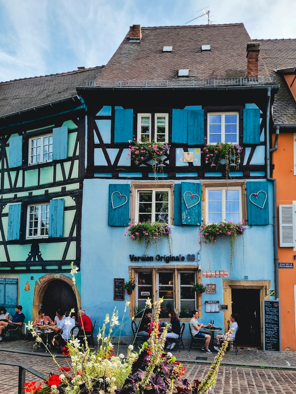 a building with blue shutters and flowers in front of it