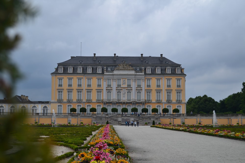 a large yellow building with lots of flowers in front of it