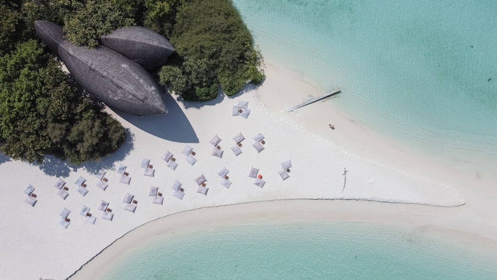 an aerial view of a beach with umbrellas and chairs