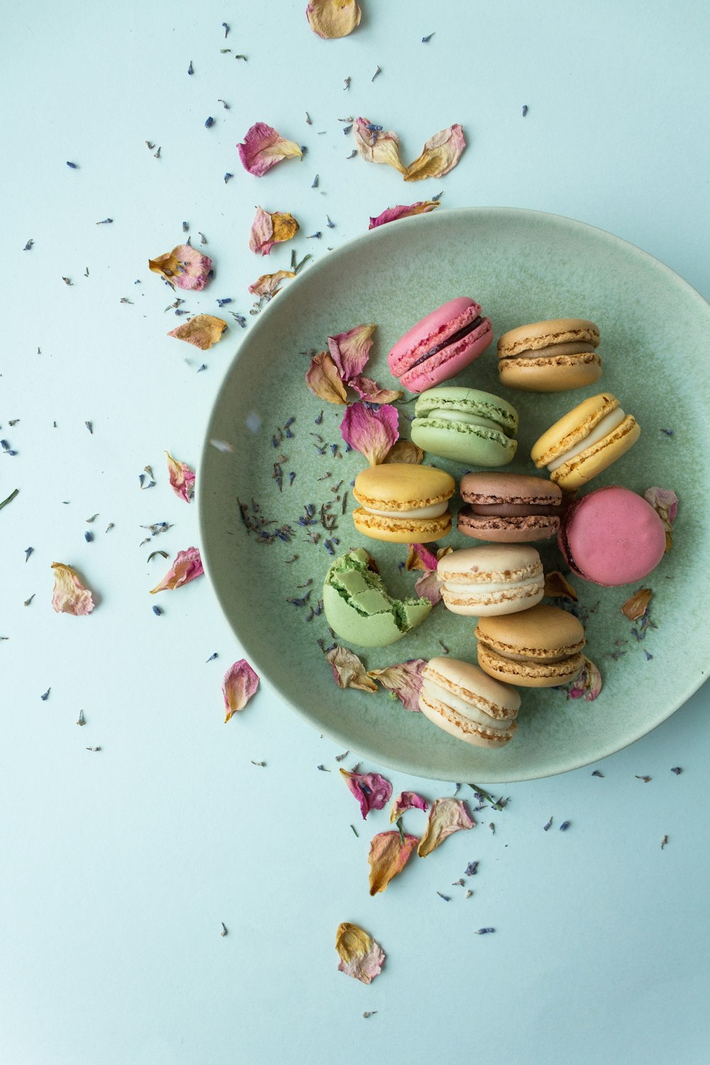a plate of colorful macaroons on a blue surface
