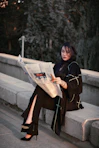 a woman sitting on a ledge reading a newspaper