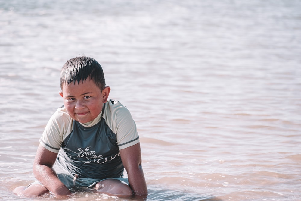 a young boy sitting on a surfboard in the water