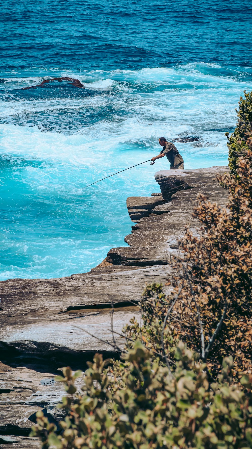 a man fishing off the edge of a cliff