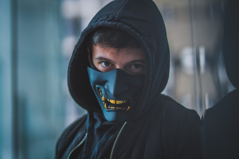 a man wearing a black mask and a black hoodie