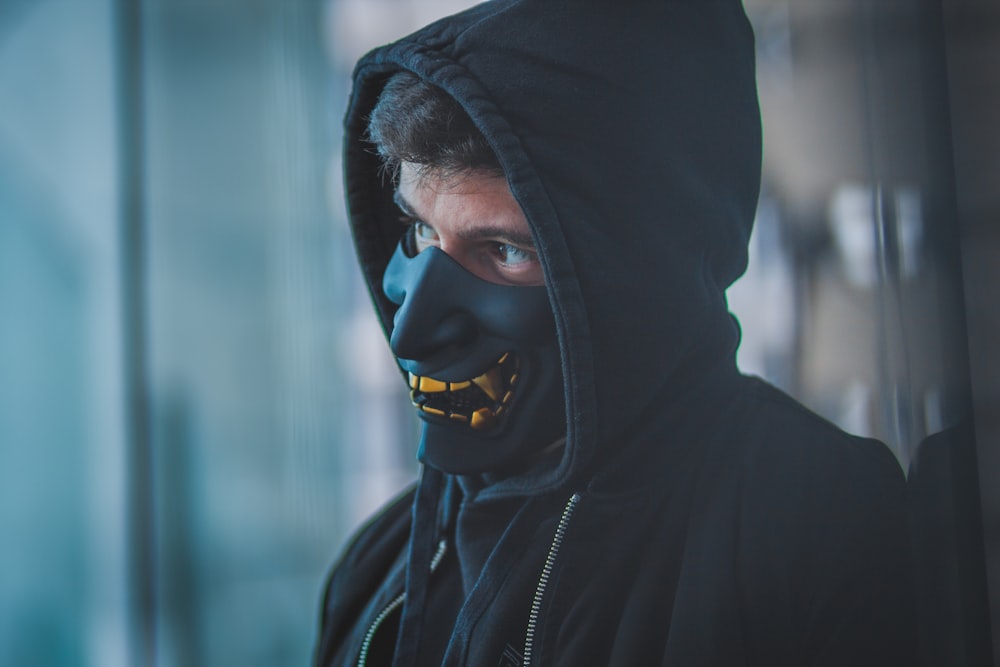 a man wearing a black mask and a black hoodie