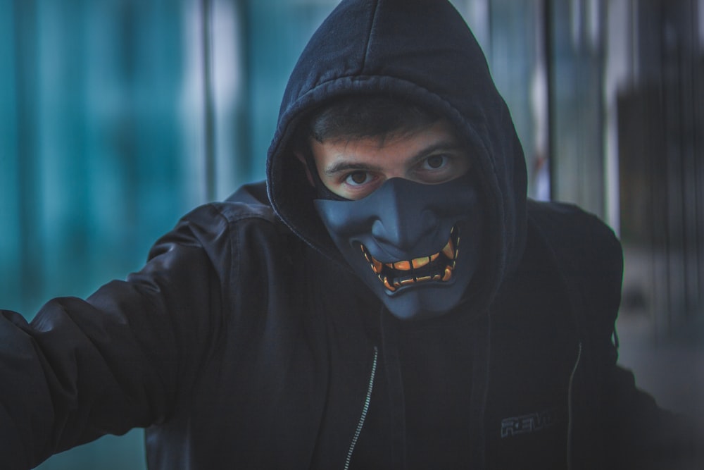 a man wearing a black mask and a black hoodie
