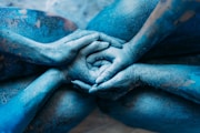 a person covered in blue powder holding their hands together