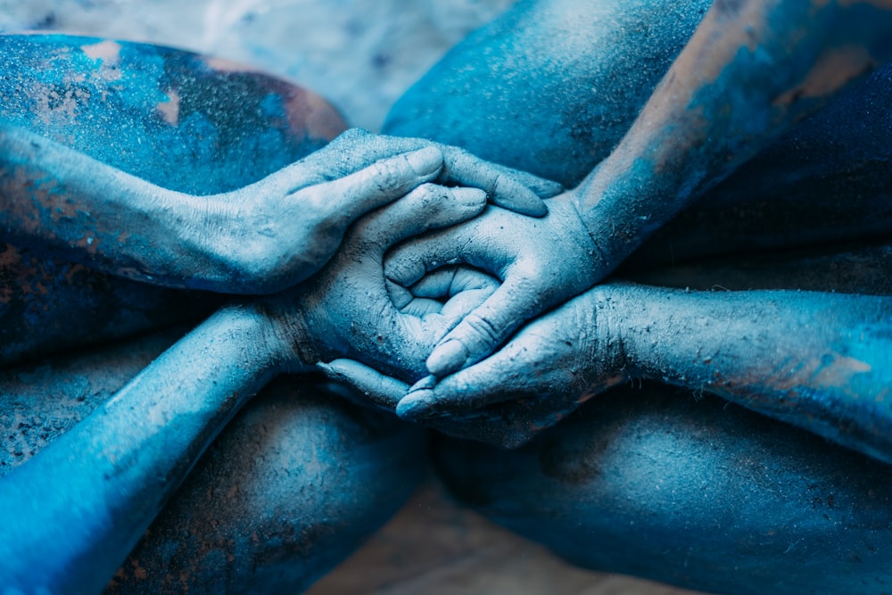 una persona coperta di polvere blu che tiene le mani unite